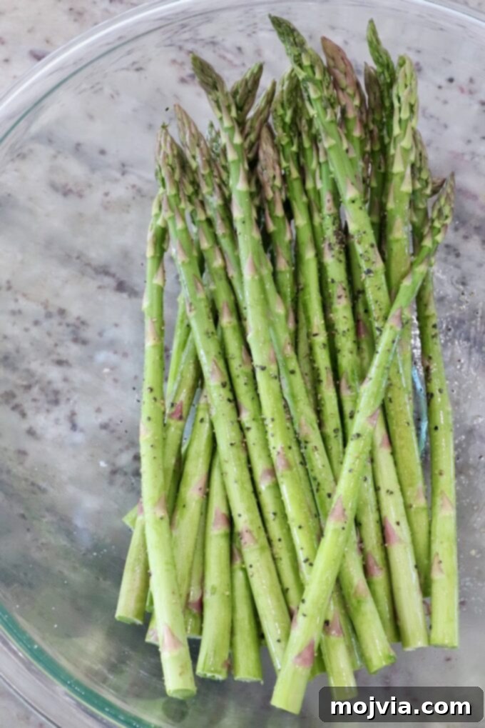 Simple Steps to Delicious Asparagus 4 Seasoned asparagus spears in a glass bowl, coated with olive oil, salt, and pepper.