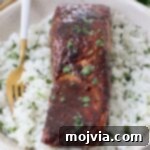 cooked glazed salmon on top of white rice in bowl with fork