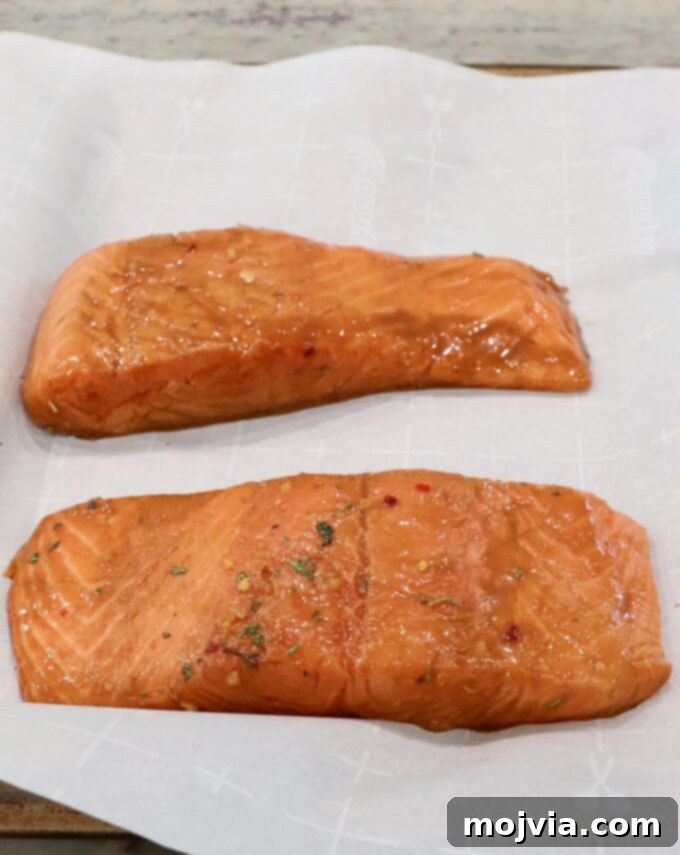 marinated pieces of salmon on parchment-lined baking sheet