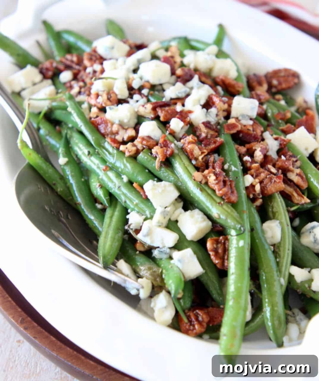 Green Beans with a Bacon, Pecan and Blue Cheese Crunch 2 Fresh cooked green beans in serving bowl topped with crumbled bacon, pecans and blue cheese