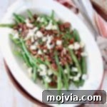 Overhead image of fresh green beans in serving bowl with pecans and blue cheese