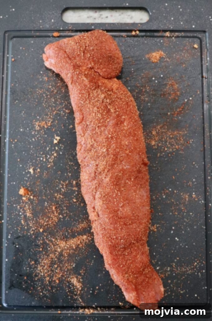 Fire-Kissed Pork Tenderloin 4 Seasoned pork tenderloin resting on a cutting board, coated evenly with BBQ rub.