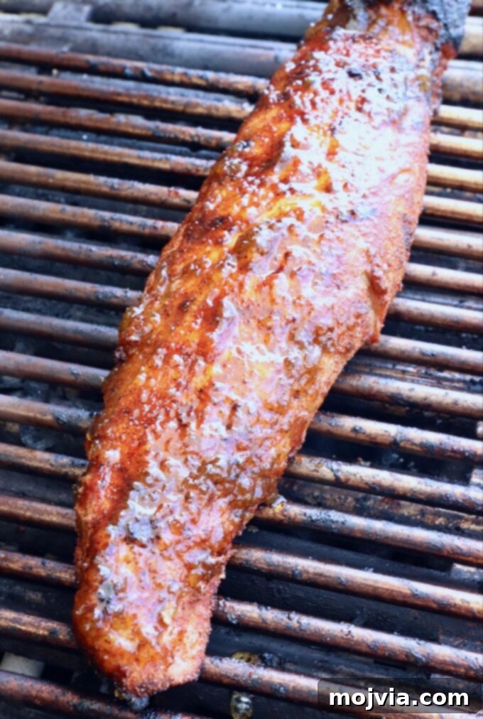 Fire-Kissed Pork Tenderloin 6 Glazed pork tenderloin cooking on the grill over indirect heat, with a shiny, appealing coating.