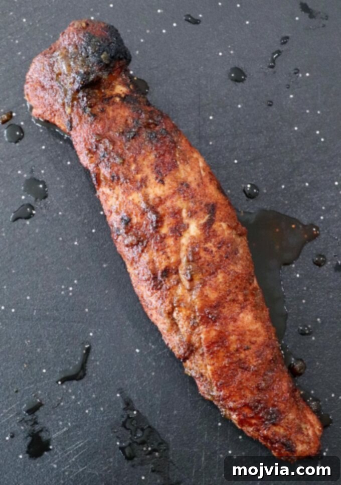 Fire-Kissed Pork Tenderloin 7 Fully cooked grilled pork tenderloin removed from the grill, resting on a cutting board.