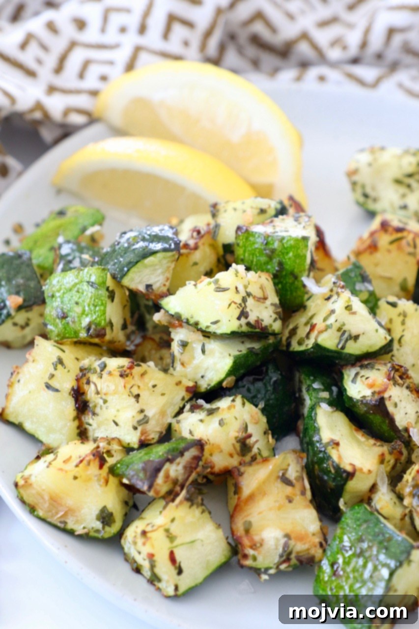 Mastering Zucchini: Your Essential Cooking Guide 2 seasoned cooked diced zucchini on plate with lemon wedges