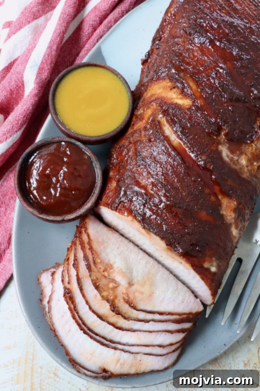Carolina Gold Mustard Magic 5 partially sliced smoked pork loin on plate with two sides of bbq sauce