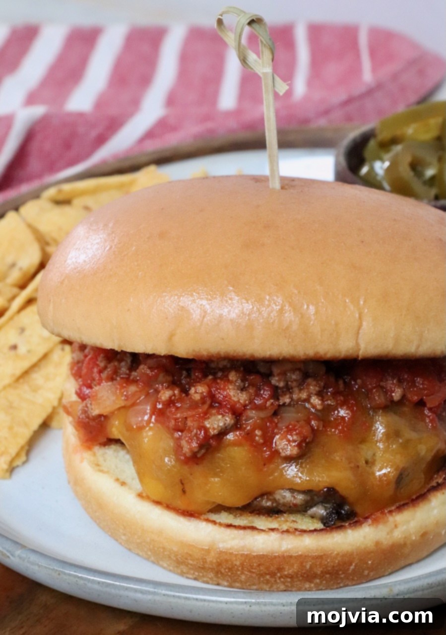 Robust Chili Burger 11 A chili cheeseburger on a plate, served alongside crispy potato chips for a satisfying meal.