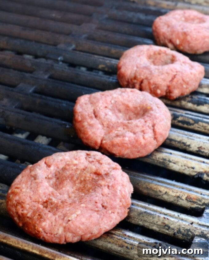 Robust Chili Burger 8 Uncooked burger patties arranged neatly on a hot grill, showing early grill marks.
