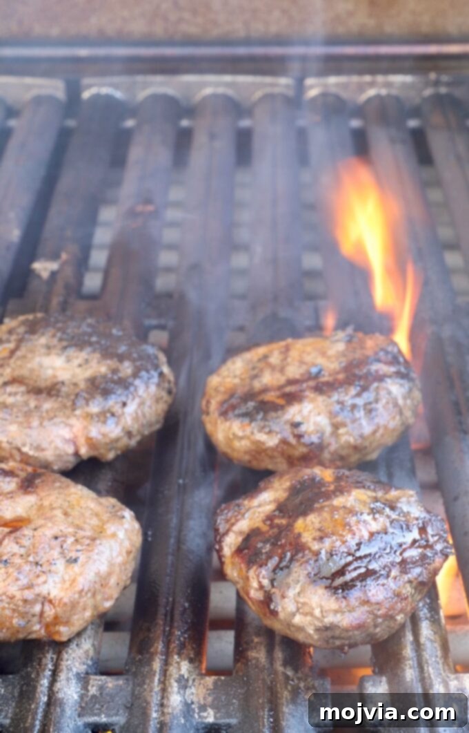 Robust Chili Burger 9 Cheeseburgers with melted cheddar cheese on top, resting on the grill during the final cooking stage.