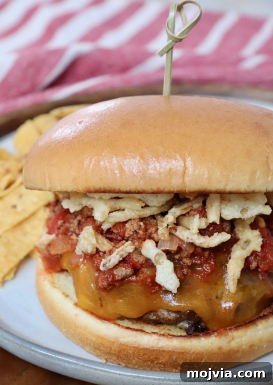 Robust Chili Burger 10 Chili cheeseburger on a plate, topped with crispy fried onion strings and ready to eat.