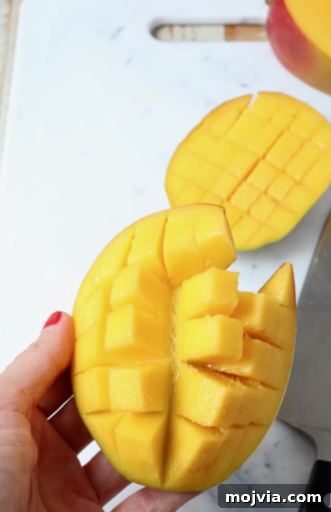 The Art of Mango Slicing 6 Hand gently pushing up on the back of a scored mango cheek, causing the cubes to fan out