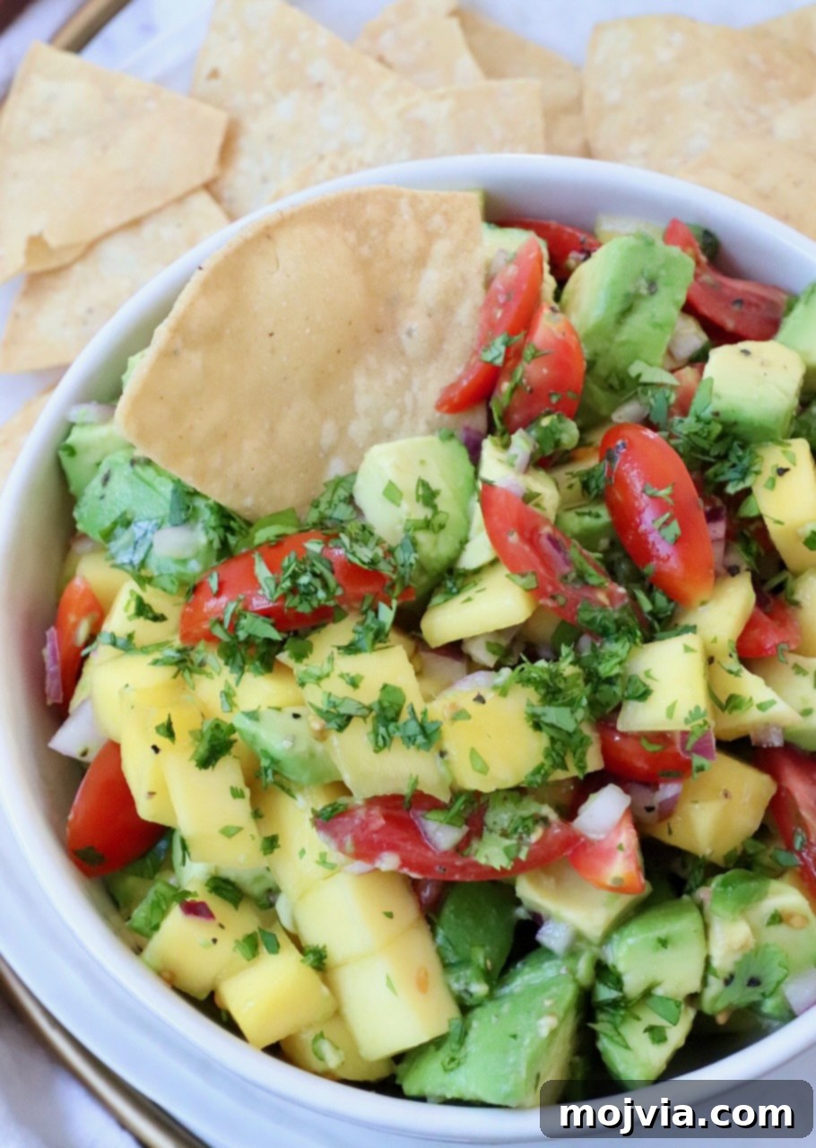 The Art of Mango Slicing 9 Vibrant mango and creamy avocado salsa in a bowl, garnished with a tortilla chip