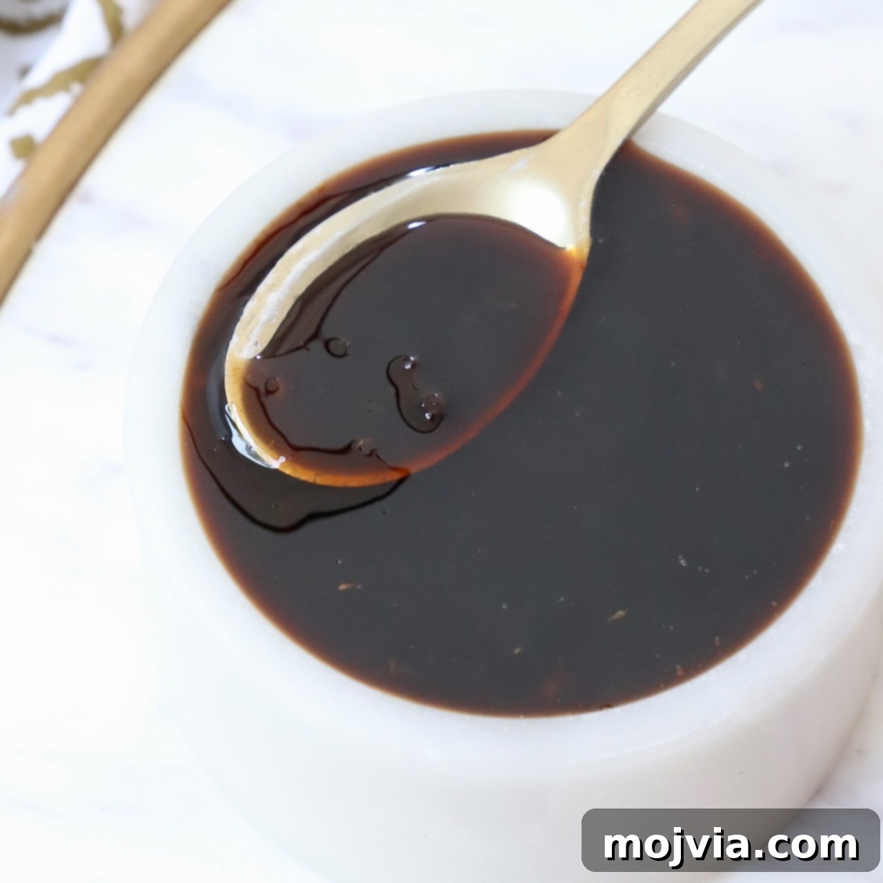 Umami Glaze 7 Close-up shot of homemade teriyaki sauce in a bowl with a small spoon, showcasing its rich, glossy texture.