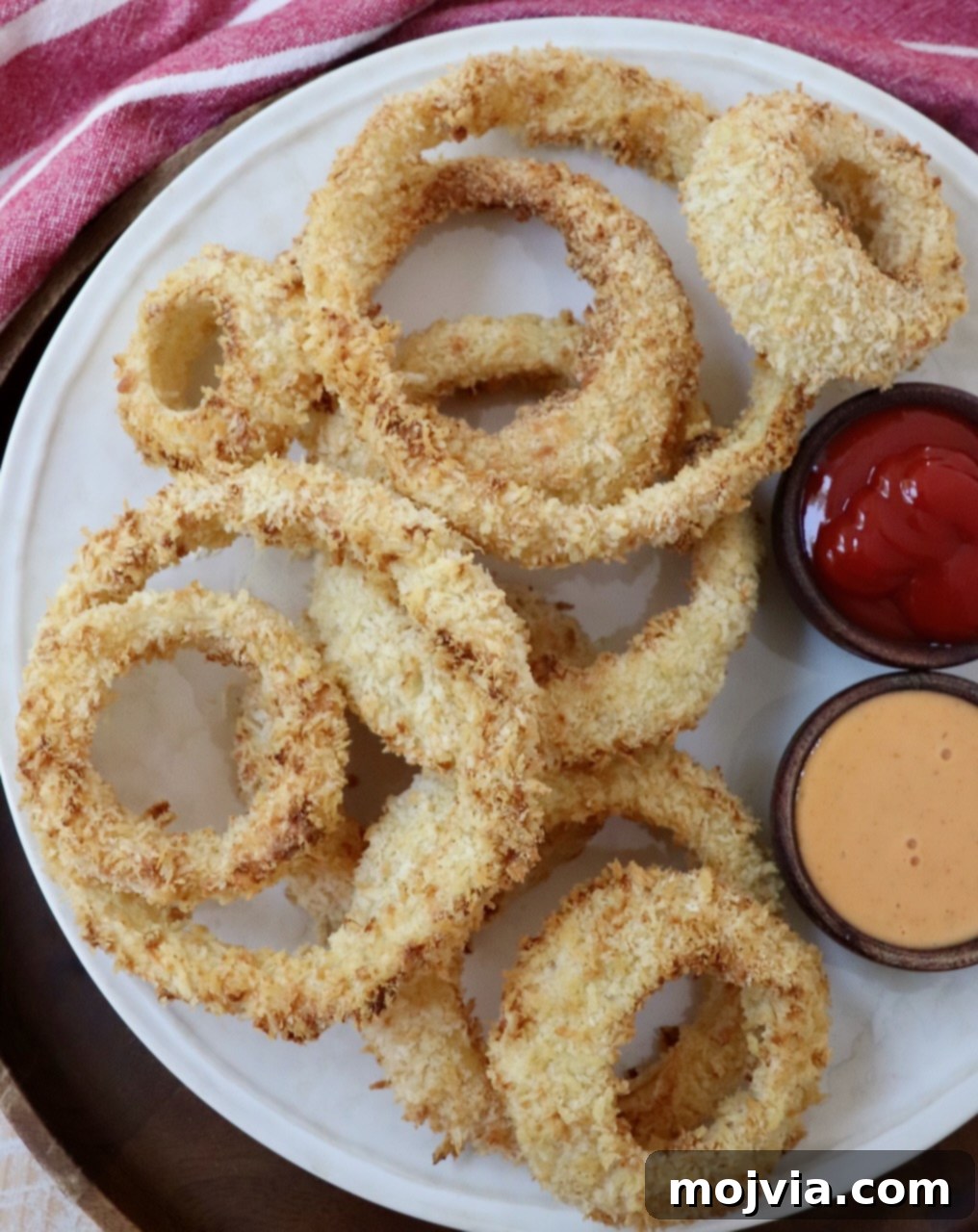 Golden & Crispy Air Fryer Onion Rings 12 air fried onion rings on a plate with various dipping sauces in small bowls