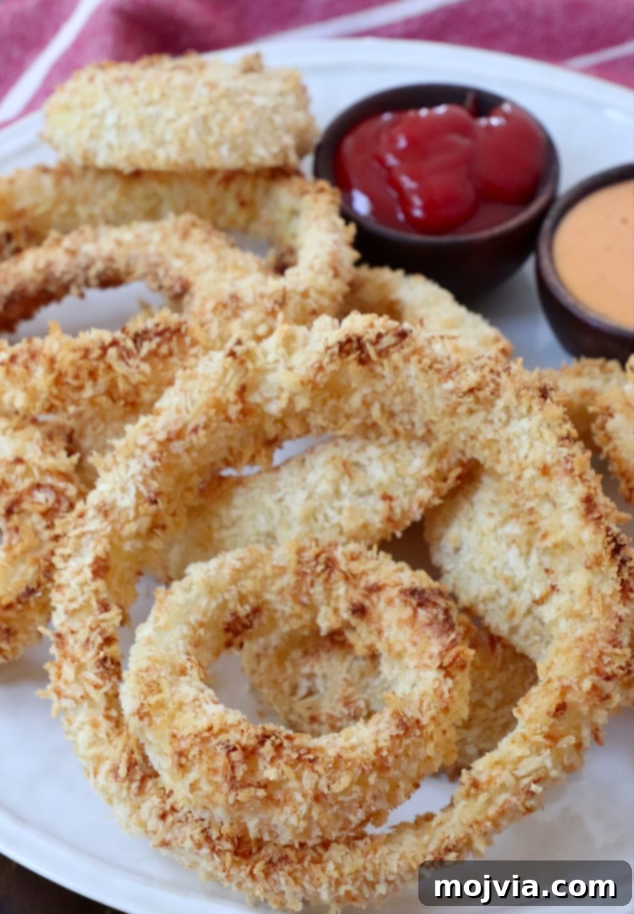 Golden & Crispy Air Fryer Onion Rings 13 air fried onion rings on a plate with small bowls of sauce on the side
