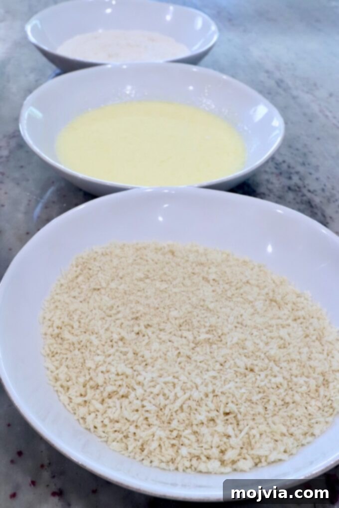 Golden & Crispy Air Fryer Onion Rings 5 three bowls lined up for a breading station: breadcrumbs, flour, and buttermilk