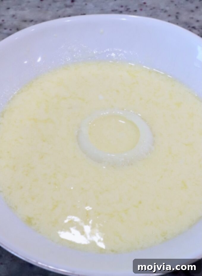 Golden & Crispy Air Fryer Onion Rings 6 a slice of onion being dipped into a bowl of buttermilk