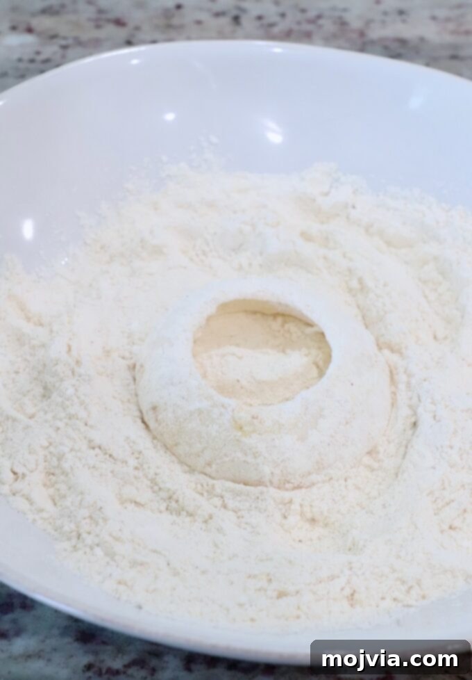 Golden & Crispy Air Fryer Onion Rings 7 a slice of onion being coated in a bowl of flour