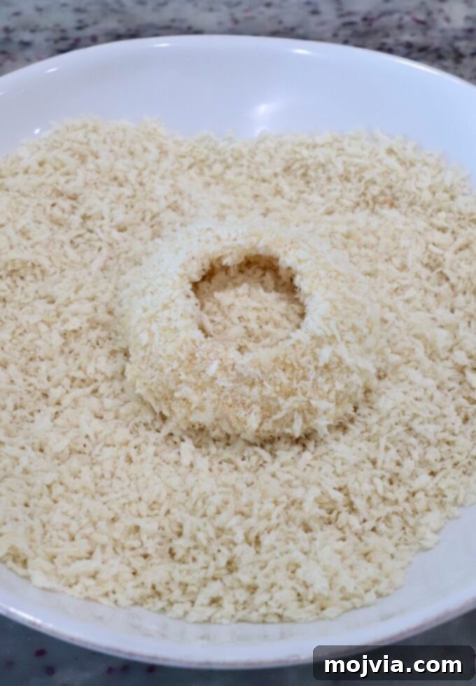 Golden & Crispy Air Fryer Onion Rings 8 a slice of onion being pressed into a bowl of breadcrumbs for coating