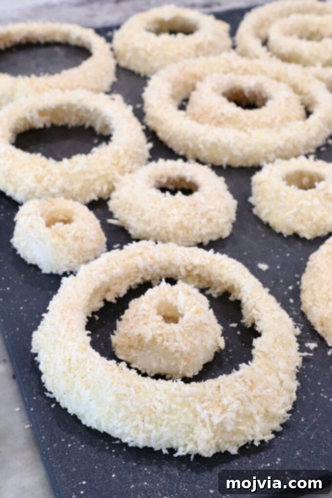 Golden & Crispy Air Fryer Onion Rings 9 coated onion rings resting on a cutting board, ready for the air fryer