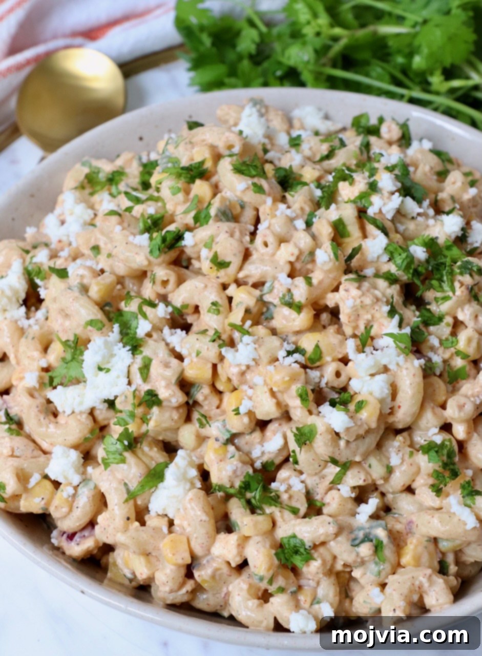 Mexican street corn pasta salad in a beautiful serving bowl, garnished with fresh cilantro and cotija cheese