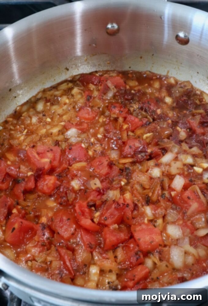Smoky Chipotle Chicken Tinga 5 diced tomatoes in pan with diced onions, spices and chicken broth
