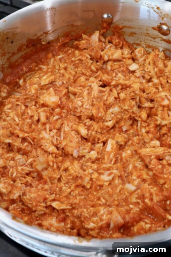 Smoky Chipotle Chicken Tinga 7 cooked, shredded chicken in tinga sauce in pan on the stove