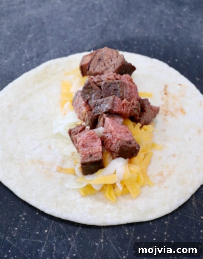 Crispy Beef Taquitos 6 tortilla on cutting board topped with shredded cheese and diced grilled steak