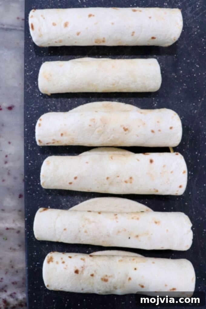 Crispy Beef Taquitos 7 rolled up uncooked taquitos on cutting board