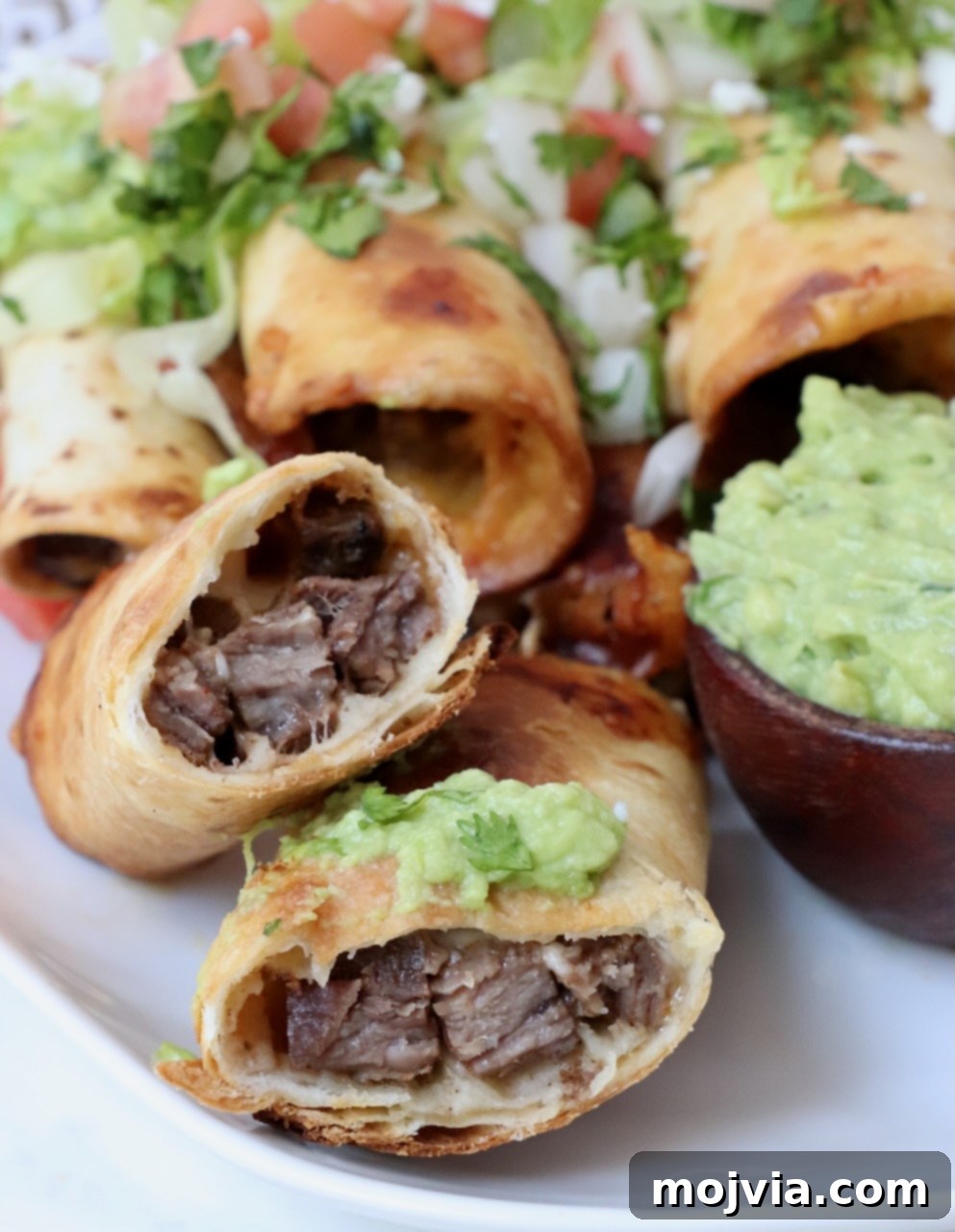 Crispy Beef Taquitos 10 steak taquito cut in half on plate with guacamole