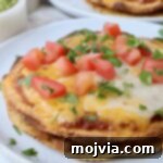 Mexican pizza on plate topped with diced tomatoes and fresh cilantro