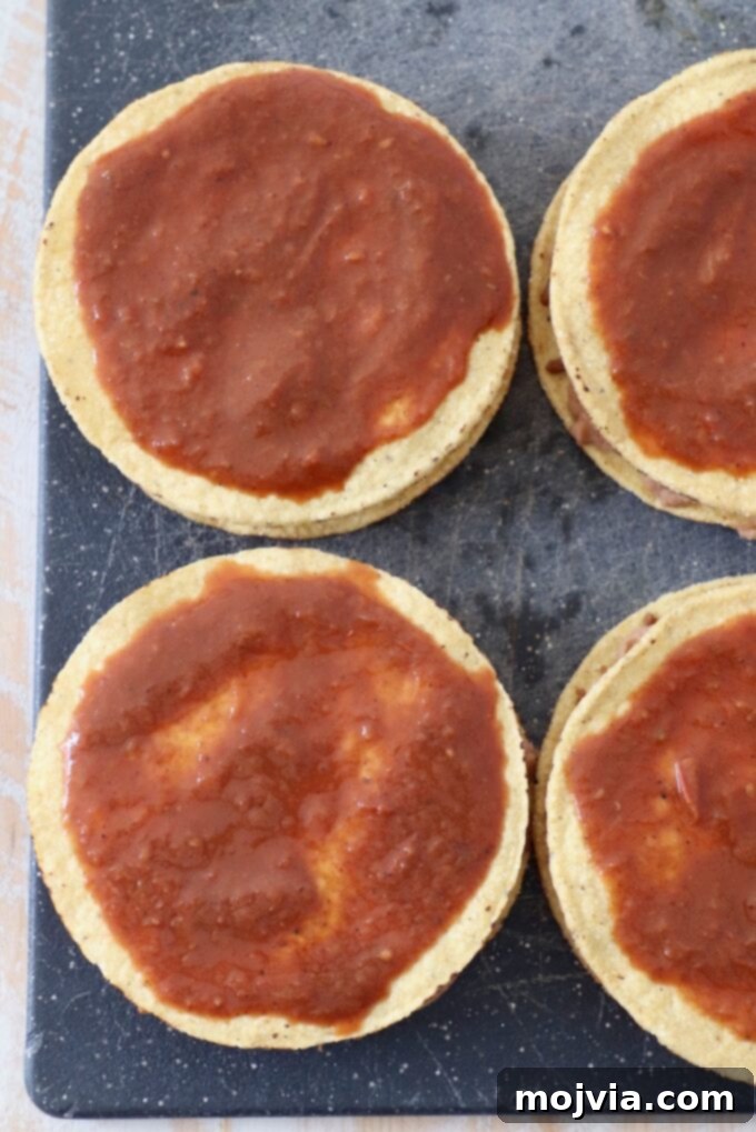 tostada shells topped with enchilada sauce on a cutting board