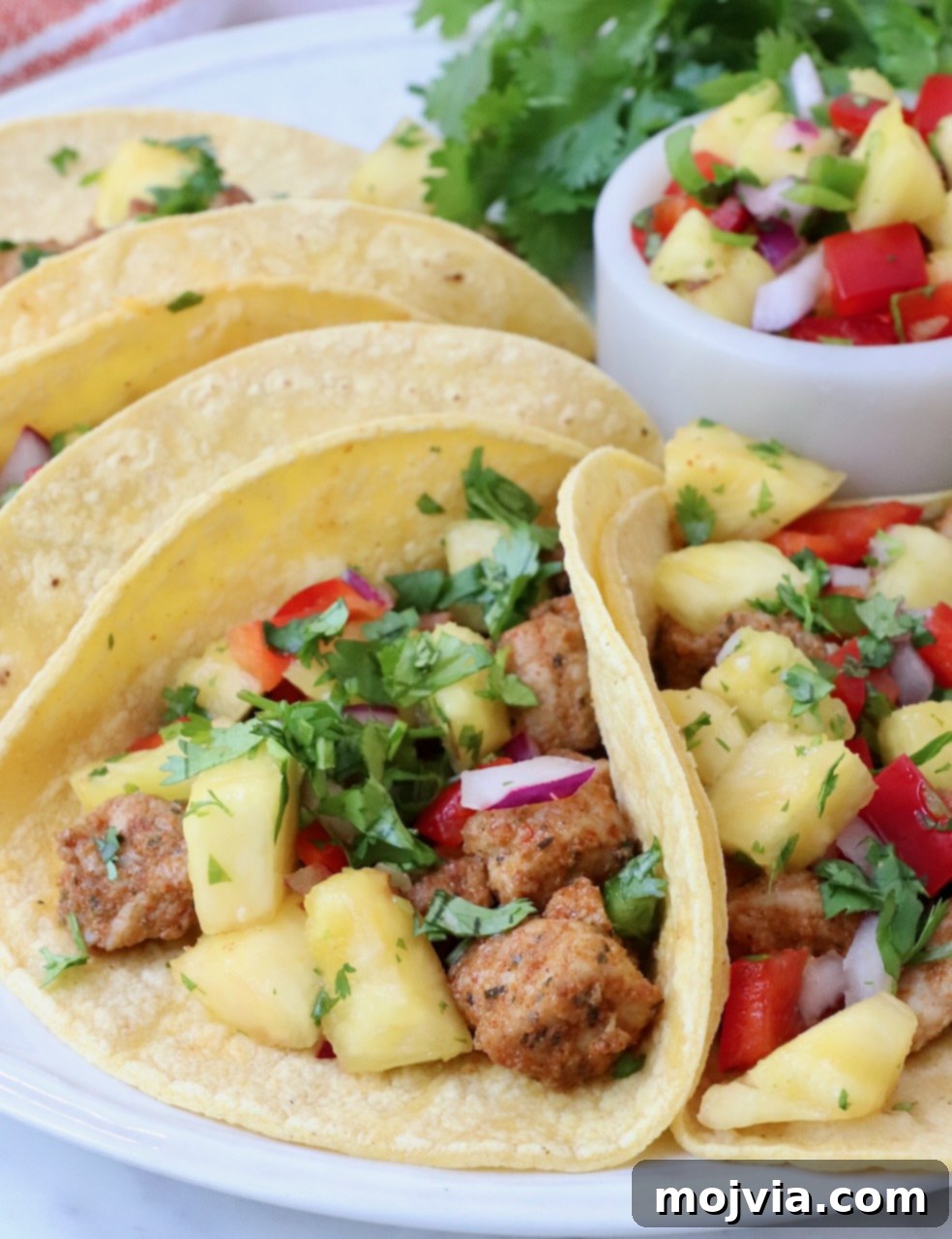 Zesty Carnitas Tacos 2 Delicious pork tacos topped with fresh pineapple salsa, served on a plate ready to eat.