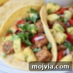 Pork tacos topped with fresh pineapple salsa on a plate.