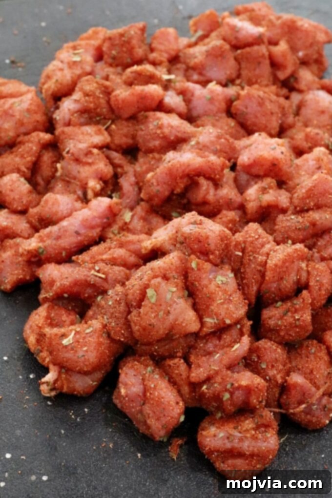 Zesty Carnitas Tacos 4 Diced pork tenderloin coated in taco seasoning on a cutting board, ready for cooking.