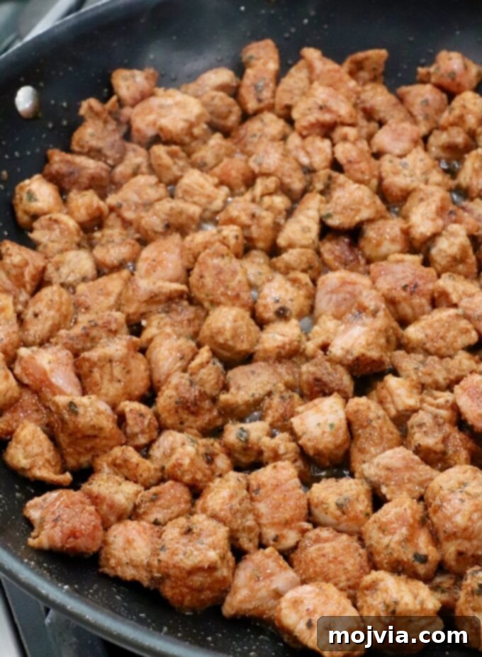Zesty Carnitas Tacos 5 Seasoned, diced pork cooking in a hot skillet on the stove, beginning to brown beautifully.