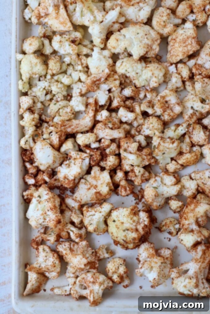 Spicy Cauliflower Tacos 4 Seasoned cauliflower florets spread on a baking sheet before roasting