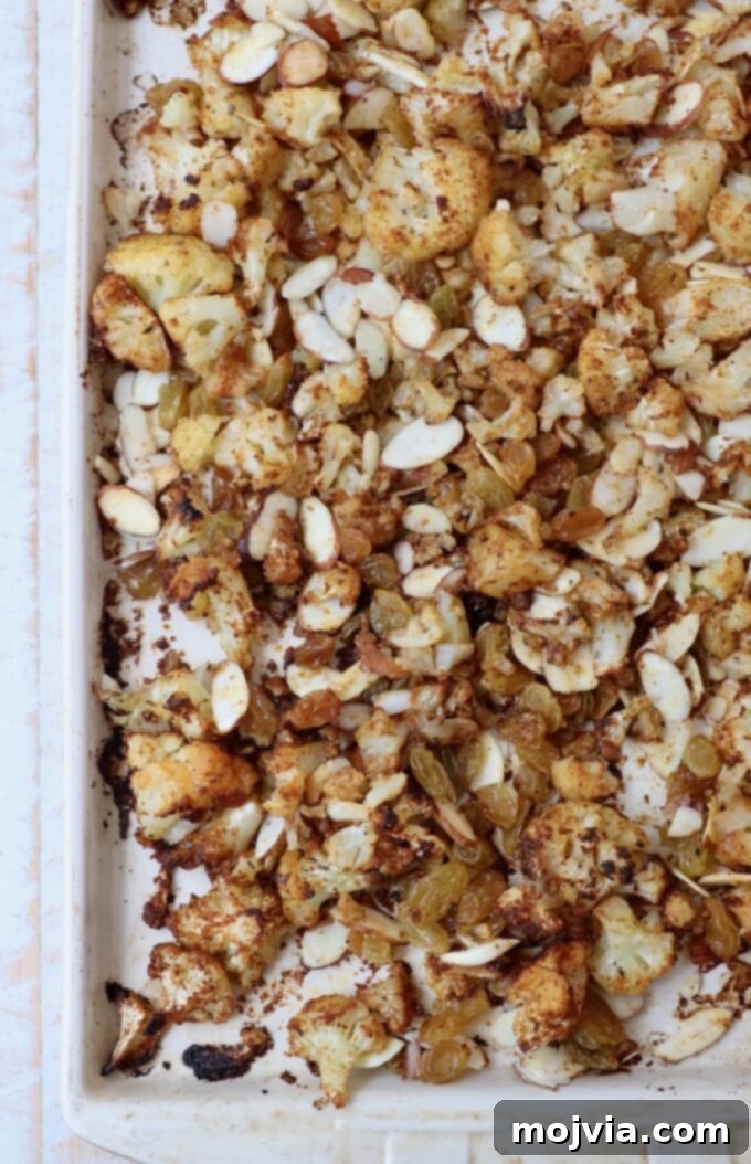 Spicy Cauliflower Tacos 5 Roasted seasoned cauliflower with almonds and raisins on a baking sheet
