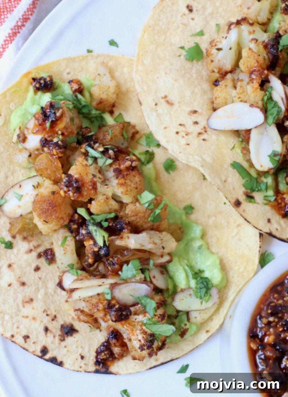 Spicy Cauliflower Tacos 6 Close-up of three cauliflower tacos arranged on a white plate