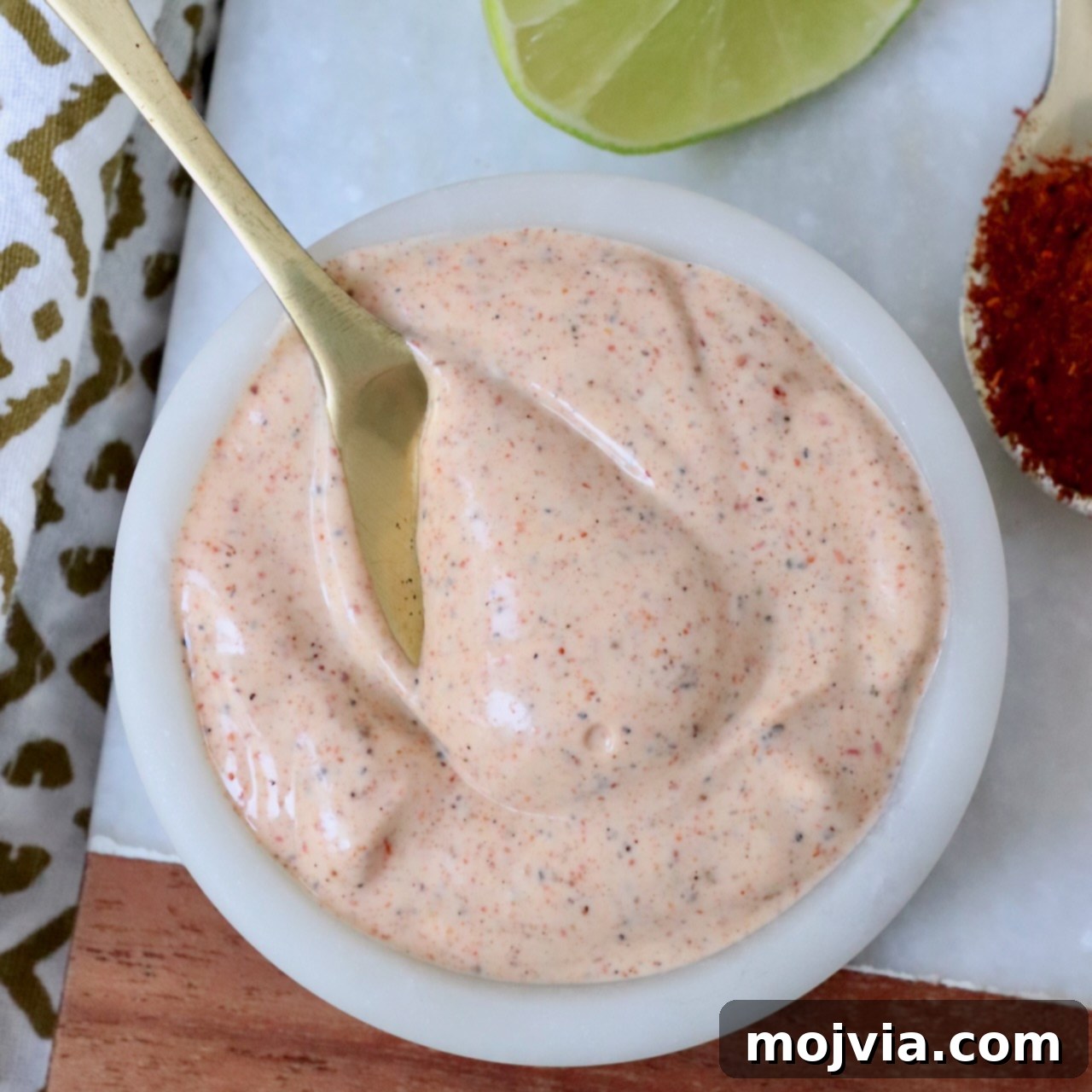 Zesty Chili Lime Vinaigrette 6 A vibrant white bowl filled with creamy chili lime dressing, accented with a golden spoon, highlighting its smooth texture and rich color.