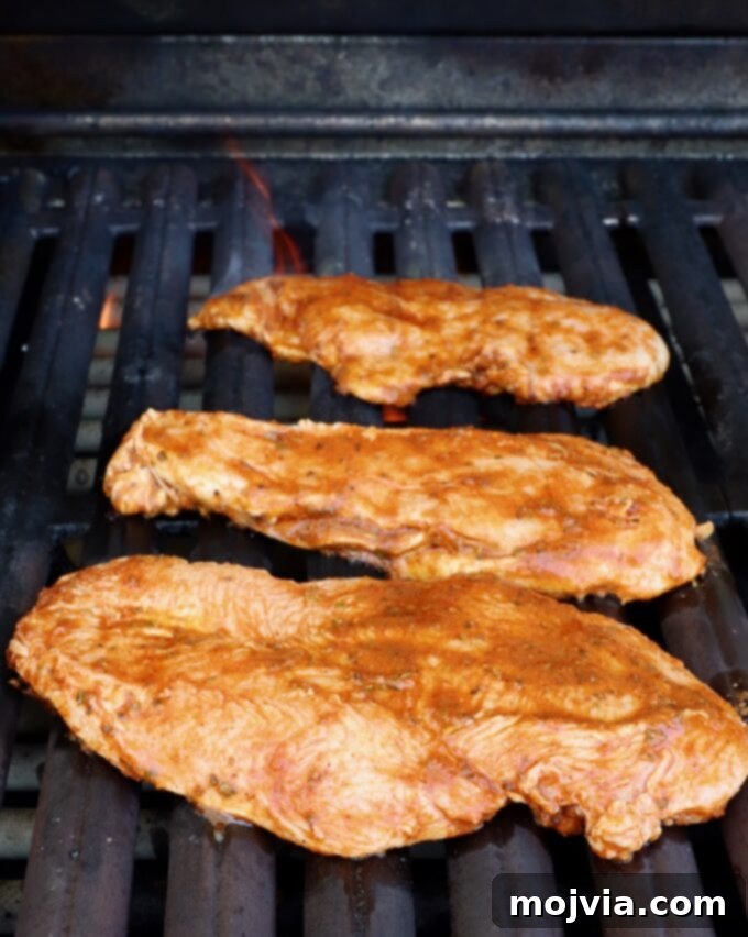 Elote Chicken Tacos 6 Marinated chicken breasts sizzling beautifully on a hot grill, showing developing char marks