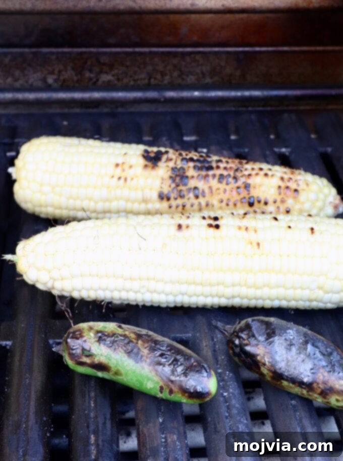 Elote Chicken Tacos 7 Fresh corn on the cob and whole jalapeños grilling side-by-side, acquiring smoky char marks