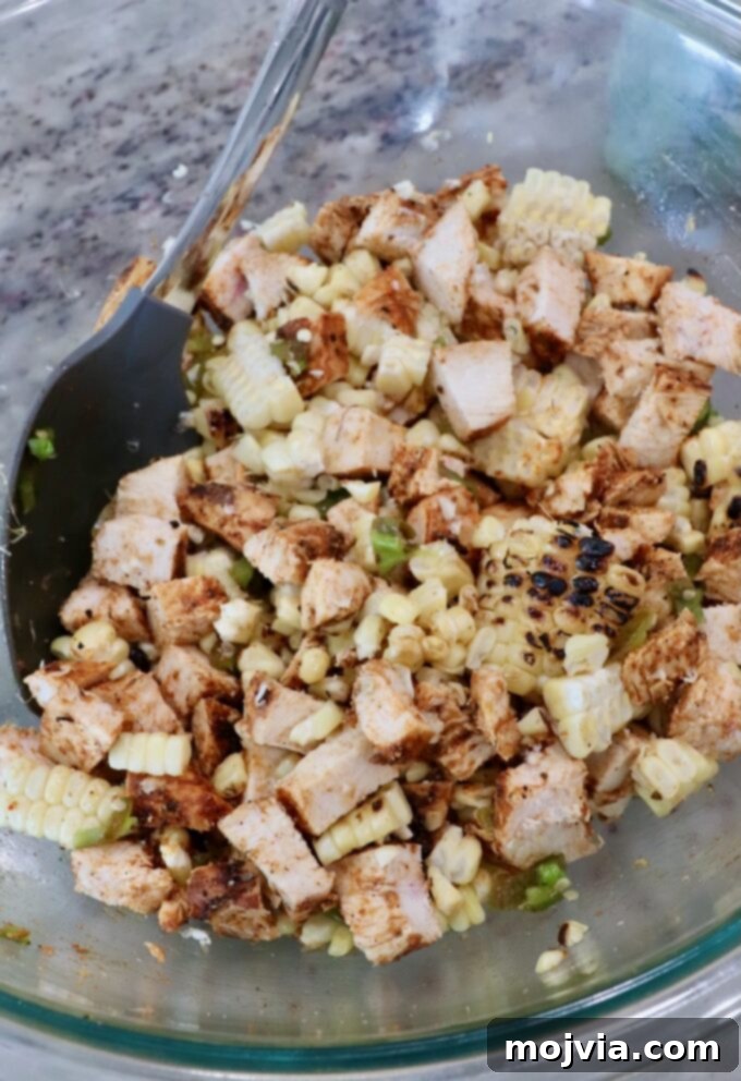 Elote Chicken Tacos 9 A glass bowl filled with diced grilled chicken, charred corn kernels, and finely diced jalapeños, ready to be combined for taco filling