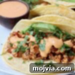 crumbled tofu taco topped with cilantro, avocado and chipotle sauce on a plate