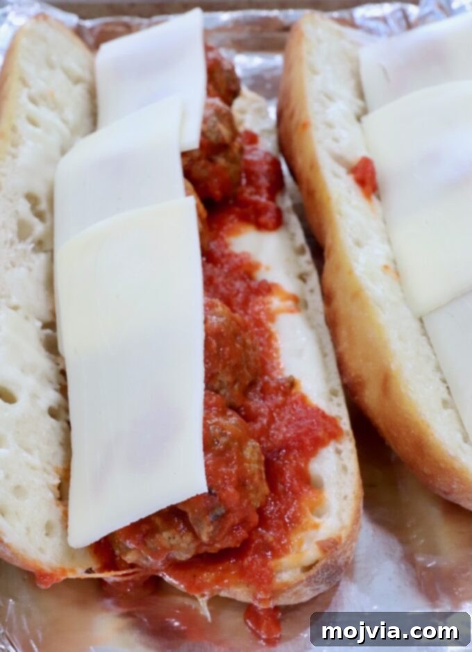 A meatball sub, fully loaded with saucy meatballs and layers of mozzarella cheese, ready for its final bake.
