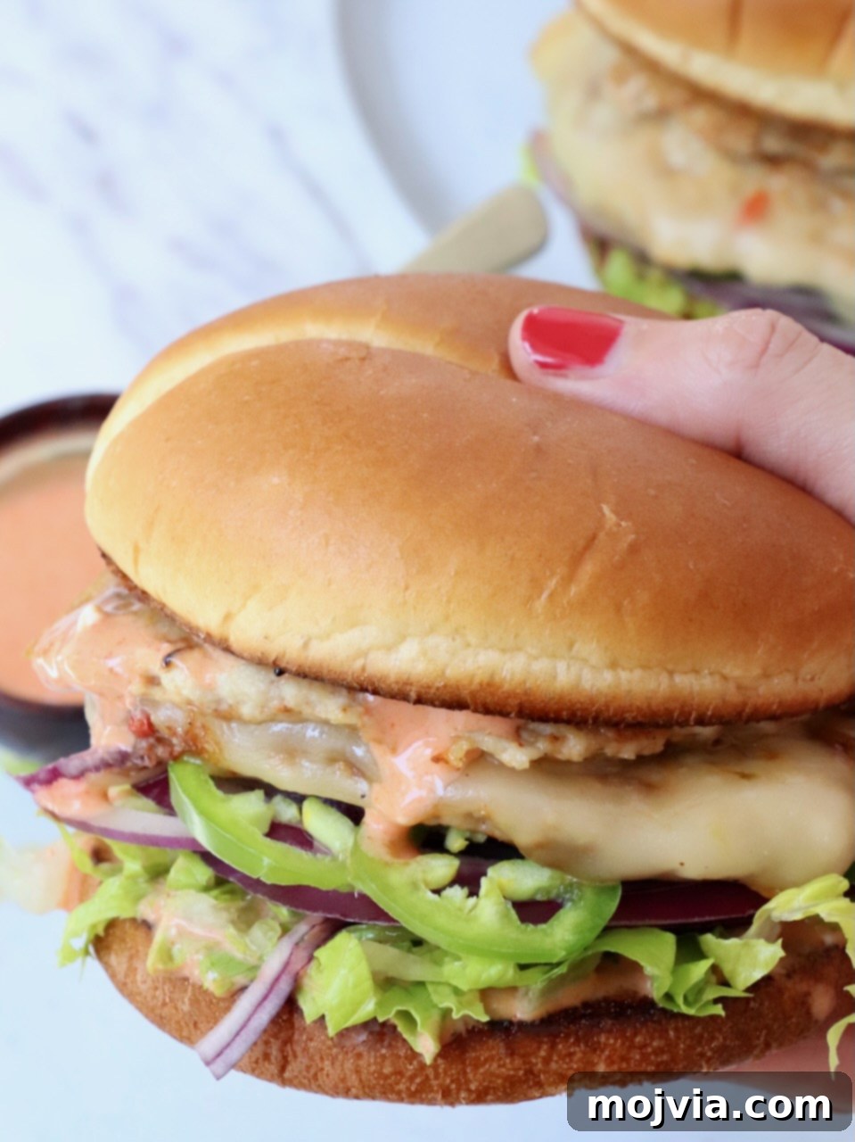 Spicy Buffalo Chicken Smash Burger 2 hand holding chicken smash burger over plate
