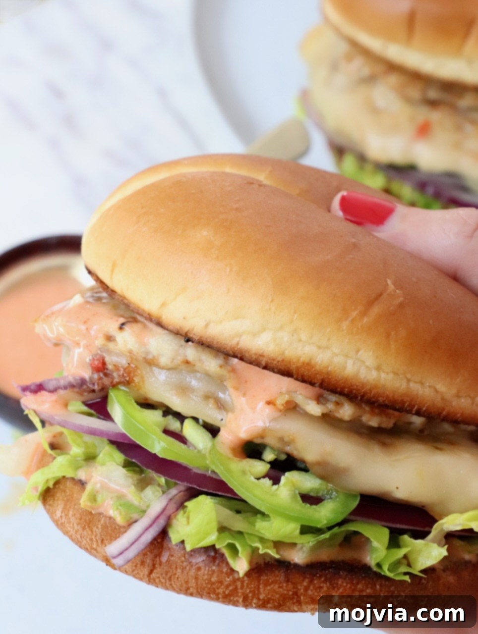 Spicy Buffalo Chicken Smash Burger 11 hand holding chicken smash burger over a plate