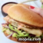 Spicy Buffalo Chicken Smash Burger 12 hand holding buffalo chicken smash burger over a plate