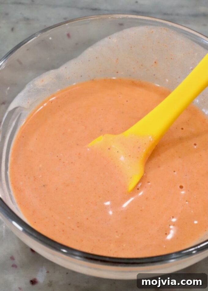 Spicy Buffalo Chicken Smash Burger 4 buffalo sauce and blue cheese dressing combined in a glass bowl with a yellow spatula