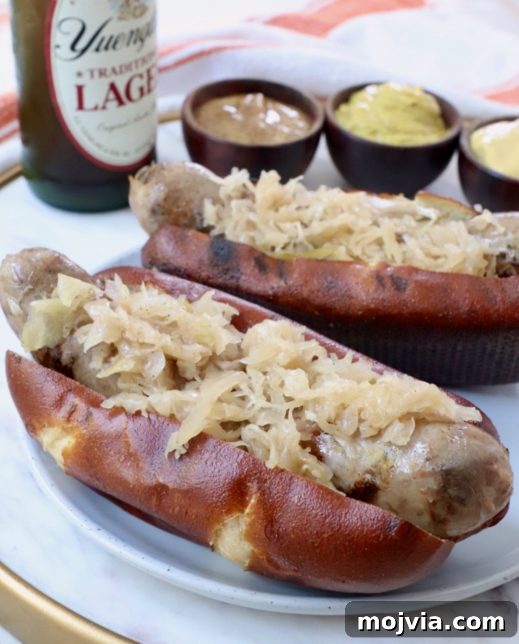 Grilled bratwurst and sauerkraut perfectly nestled in a pretzel bun, served on a rustic plate.